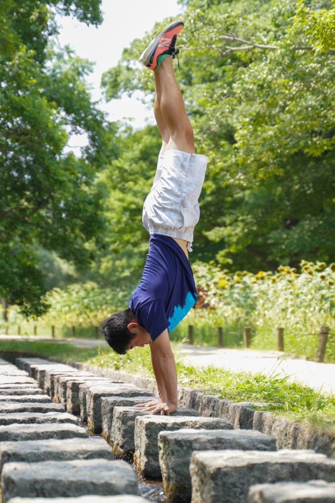 自然の中でカリステニクス（倒立）を行うトレーナー